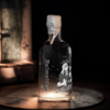 A single bottle of Bal Maiden Gin, illuminated on a rustic surface, featuring detailed artwork on the glass and a wax-sealed top, set against a dark, moody background with subtle lighting.