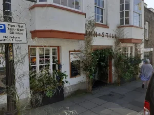 Exterior of Inn & Still in Helston, Cornwall, decorated with lush greenery for Helston Flora Day, with a festive atmosphere as locals and visitors stroll by