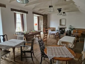 The Anson Bar at Inn & Still, featuring a rustic and cosy interior with wooden floors, eclectic chairs, lace tablecloths, and exposed stone walls, creating a warm and inviting atmosphere.